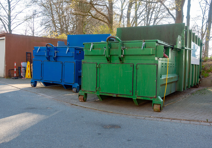 two garbage compactors are standing in the courtyard of a hospital